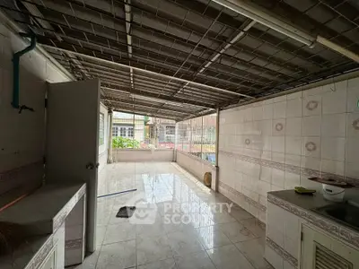 Spacious tiled outdoor area with partial roof and open view, ideal for versatile use.