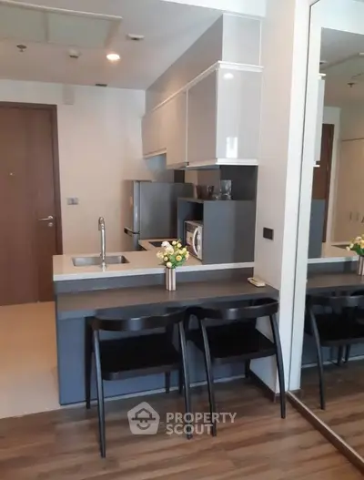 Modern compact kitchen with sleek cabinetry and breakfast bar in a stylish apartment.