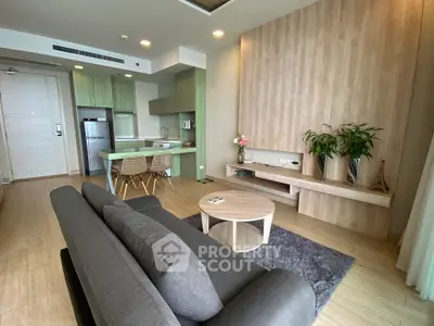 Modern living room with open kitchen, stylish decor, and cozy seating area.