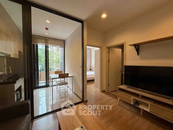 Modern apartment interior with open kitchen and living area, featuring a balcony view.