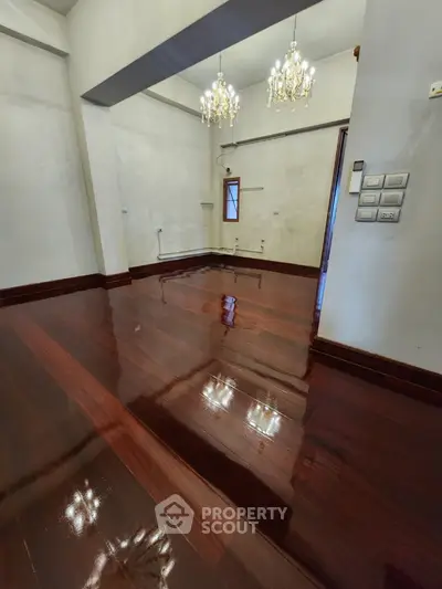 Spacious room with polished wooden floors and elegant chandeliers