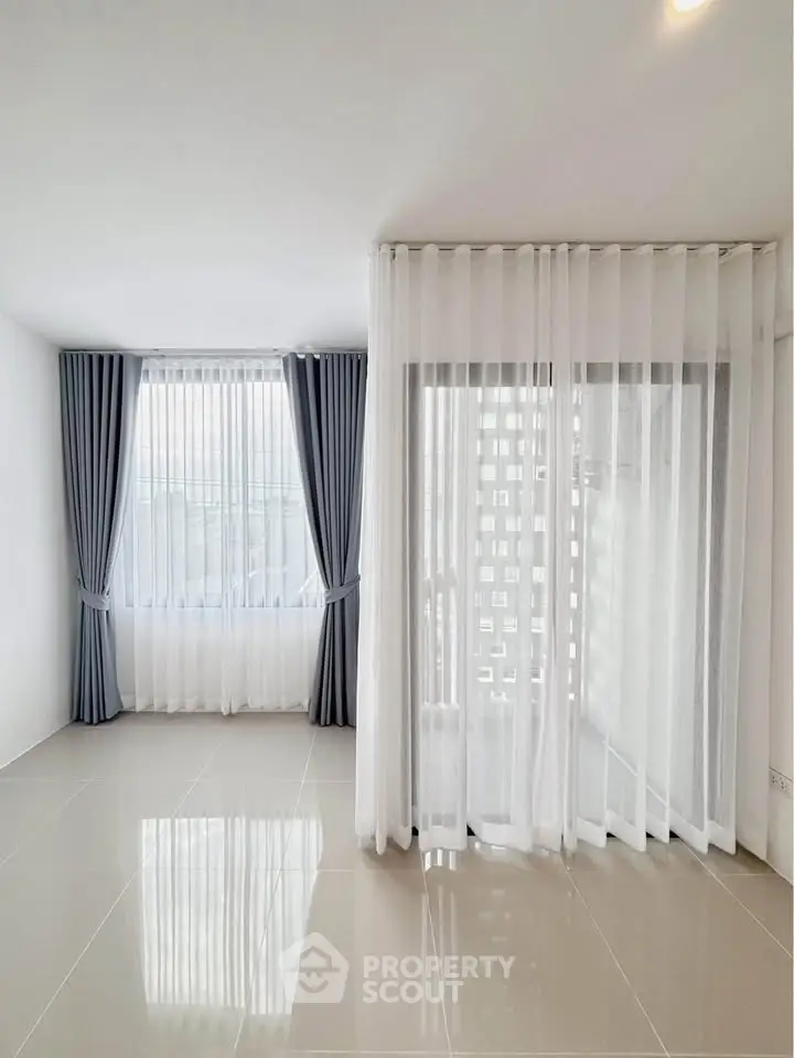 Spacious empty room with large windows and elegant curtains, perfect for customization.