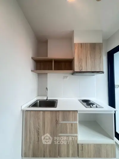 Modern compact kitchen with sleek wooden cabinets and electric stove