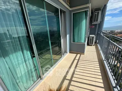 Spacious balcony with stunning city view and glass sliding doors in modern apartment.
