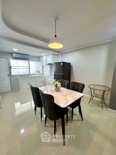 Modern kitchen with dining area featuring sleek black chairs and a marble table, ideal for stylish living.