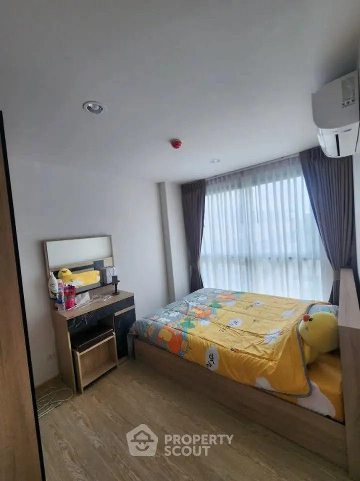 Cozy bedroom with large window and modern furnishings, perfect for relaxation and comfort.