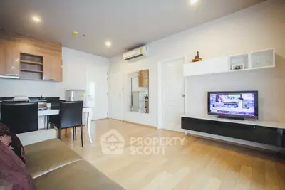 Modern living room with open kitchen, sleek furniture, and wooden flooring in a cozy apartment.