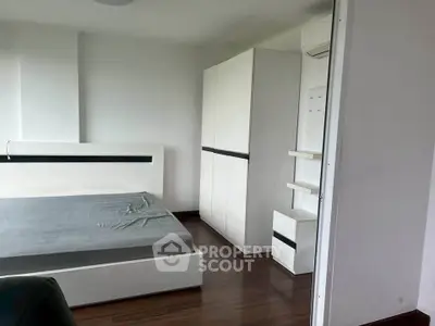 Modern minimalist bedroom with sleek white furniture and wooden flooring.