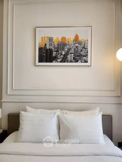 Elegant bedroom with modern cityscape artwork above bed, featuring plush white pillows and stylish decor.