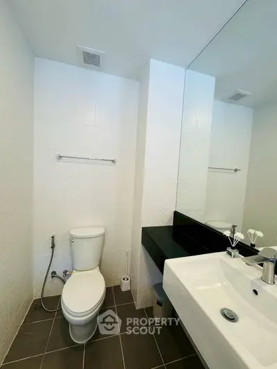 Modern bathroom with sleek fixtures and large mirror in a contemporary apartment.