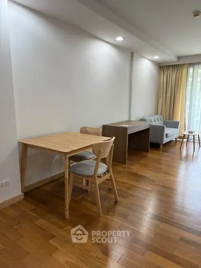 Spacious living room with wooden flooring and modern furniture in a bright apartment.