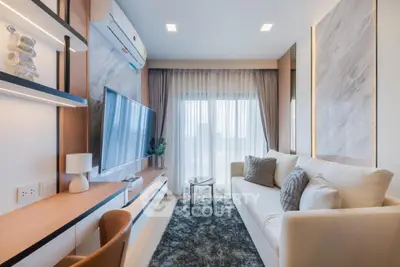 Modern living room with stylish decor and large TV, featuring cozy seating and natural light.