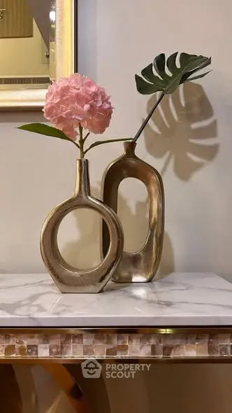 Elegant interior decor with modern vases and floral arrangement on a marble table.