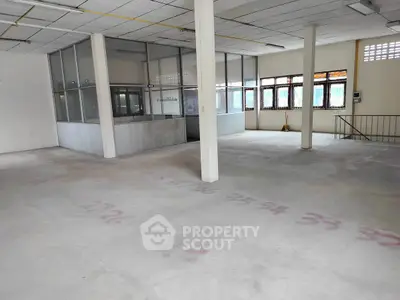 Spacious industrial space with large windows and partitioned office area, ideal for business setup.