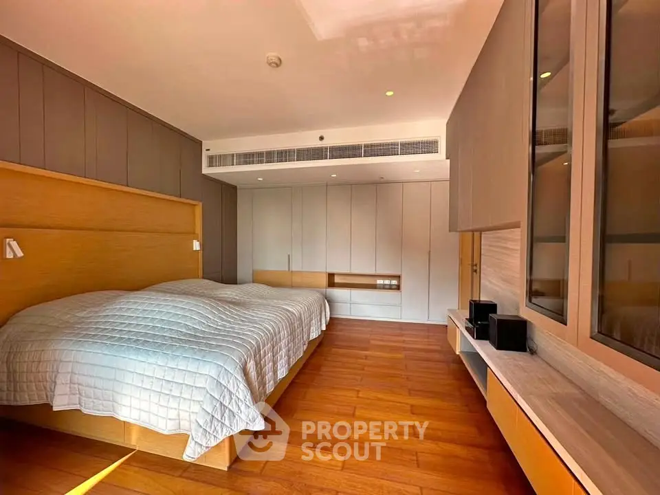 Spacious modern bedroom with wooden flooring and stylish built-in storage.