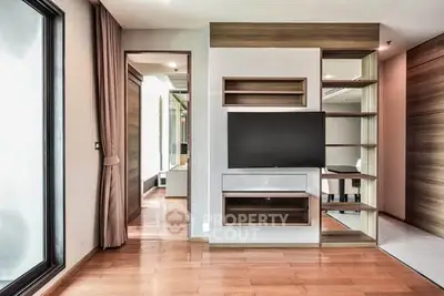 Modern living room with built-in TV unit and wooden flooring in a stylish apartment.