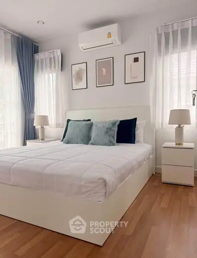 Modern bedroom with stylish decor, featuring a cozy bed, elegant lamps, and framed art on the wall.