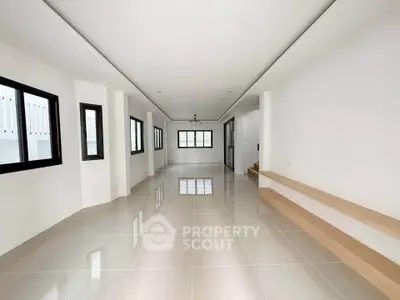 Spacious modern living room with sleek tile flooring and large windows for natural light.