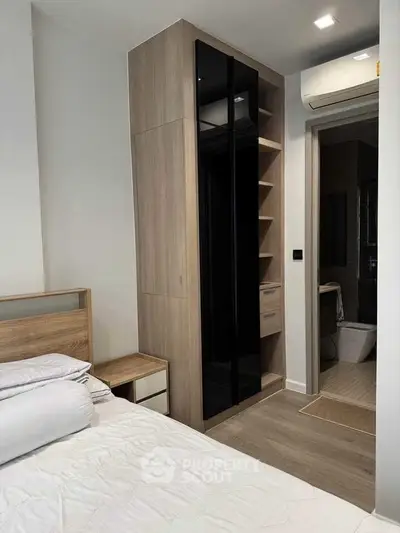 Modern bedroom with sleek wardrobe and ensuite bathroom in stylish apartment.