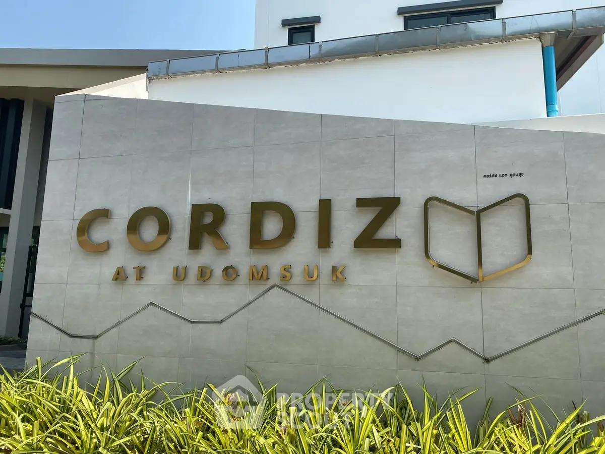 Modern building entrance with Cordiz at Udomsuk signage, sleek design and lush greenery.