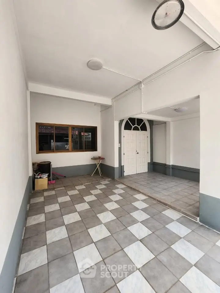 Spacious tiled entrance with white double doors and large window, perfect for welcoming guests.