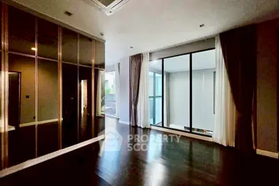 Spacious modern living room with floor-to-ceiling windows and elegant dark wood flooring.