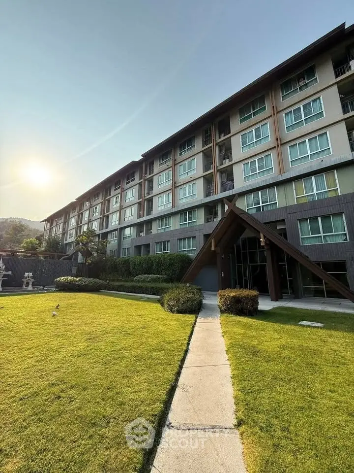 Modern apartment building with lush green lawn and clear blue sky