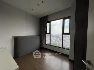 Spacious bedroom with large window offering stunning city views, perfect for urban living.