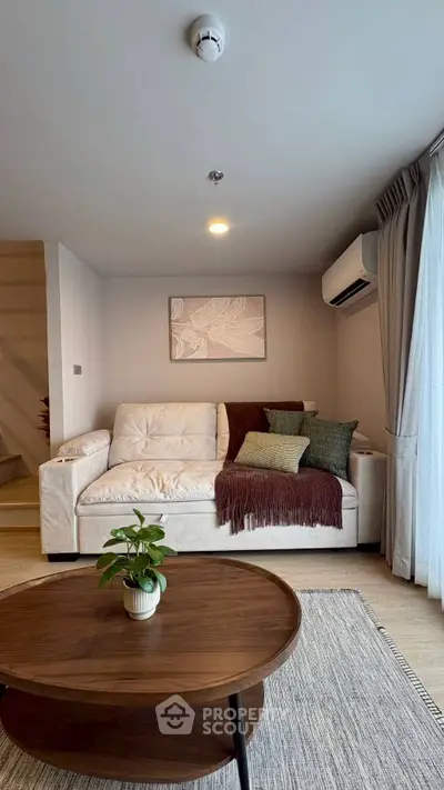 Cozy living room with modern decor, featuring a plush sofa, stylish coffee table, and natural light from large windows.