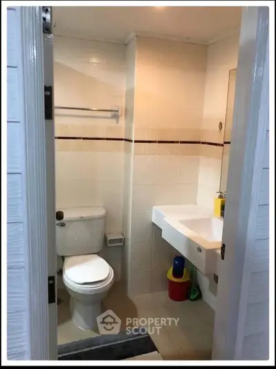 Compact bathroom with modern fixtures and tiled walls, featuring a toilet and sink.