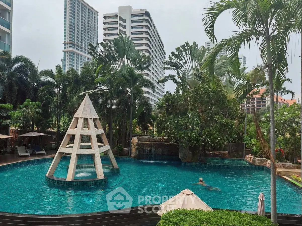 Luxurious pool area with tropical landscaping and modern high-rise buildings in the background.