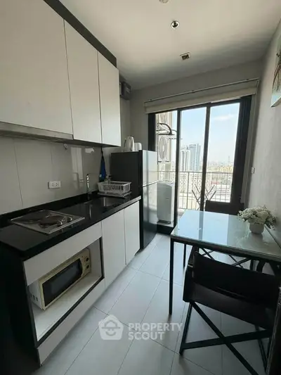 Modern kitchen with city view, sleek cabinets, and dining area in a high-rise apartment.