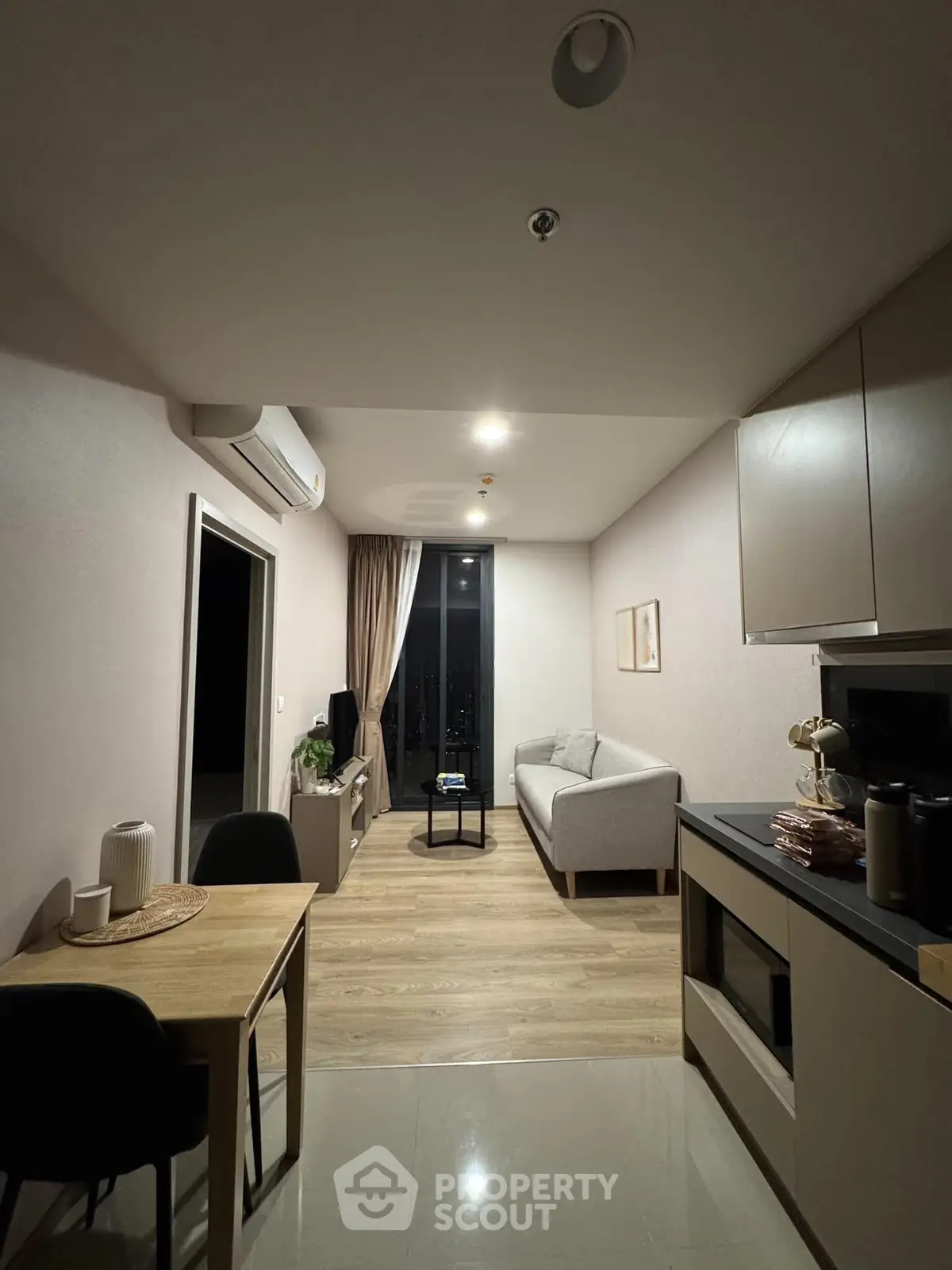 Modern living room with sleek furniture and open kitchen layout in a cozy apartment.