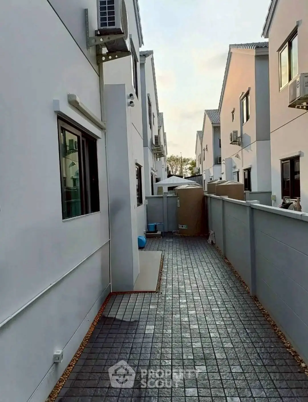 Modern townhouse exterior with paved walkway and air conditioning units