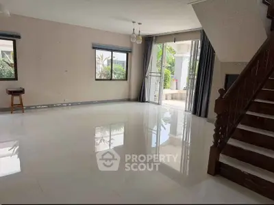 Spacious living room with large windows and garden view, perfect for family gatherings.