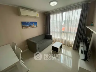 Modern living room with sleek furniture and large window offering natural light.