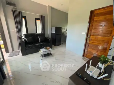 Modern living room with sleek black sofa, glass coffee table, and stylish decor in a contemporary home.