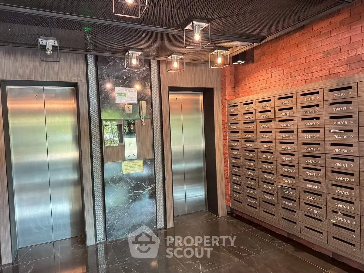 Modern apartment building lobby with elevators and mailboxes, featuring sleek design and contemporary lighting.