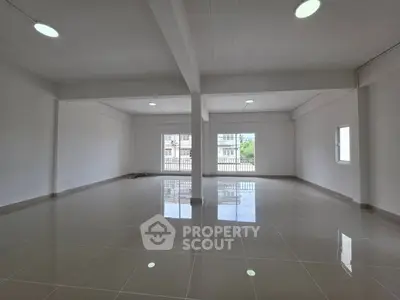 Spacious open-plan interior with glossy tiled floors and large windows.