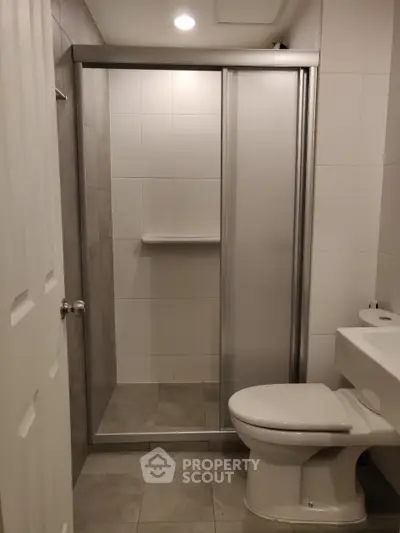 Modern bathroom with sleek shower and toilet in neutral tones.