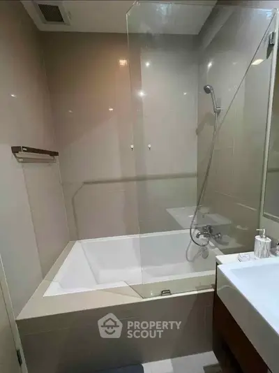 Modern bathroom with sleek bathtub and shower combination in a contemporary apartment.