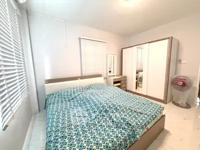 Spacious bedroom with modern furniture and ample natural light from large windows.