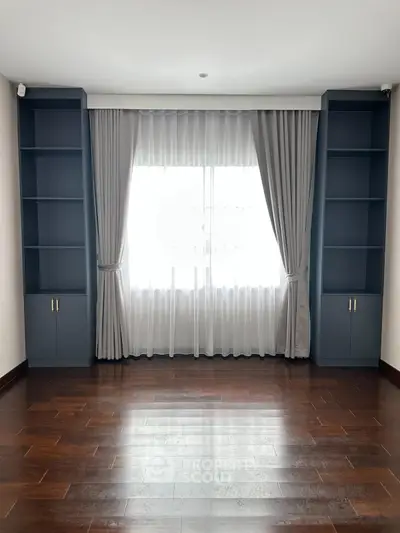 Spacious room with elegant hardwood floors and built-in shelving, perfect for a stylish living area.