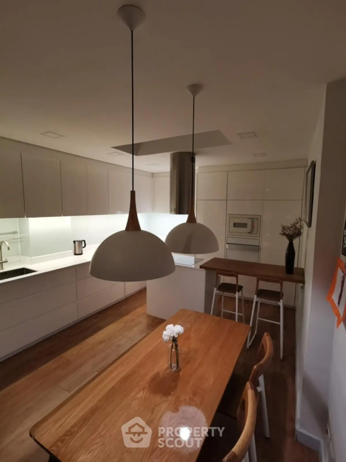 Modern kitchen with sleek white cabinets and wooden dining table