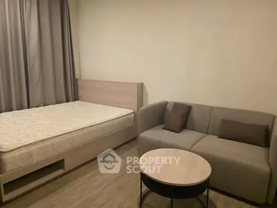 Cozy bedroom with modern furniture and neutral tones, featuring a comfortable bed and stylish sofa.