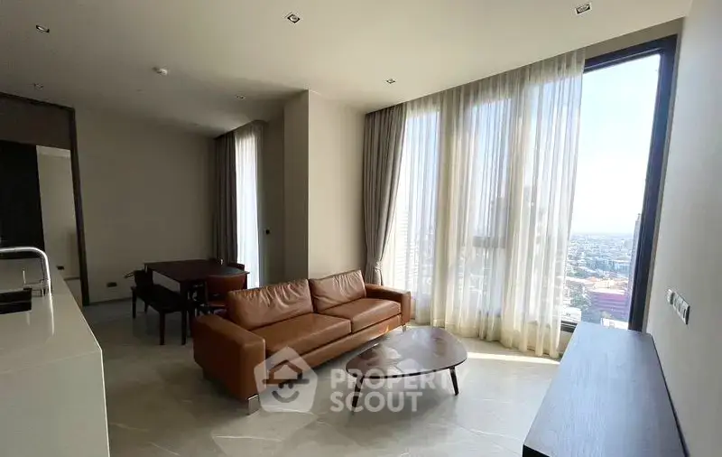 Spacious modern living room with large windows and city view, featuring elegant furniture.