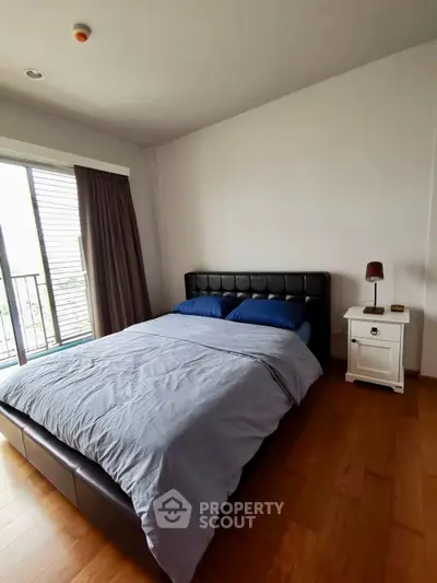 Cozy bedroom with modern furnishings and natural light from large window.