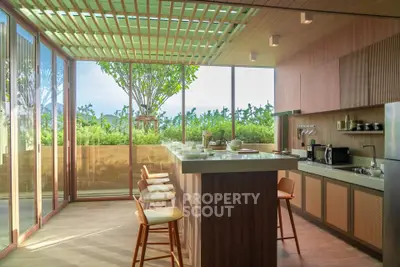 Luxurious modern kitchen with open layout and stunning garden view, featuring sleek appliances and stylish bar seating.