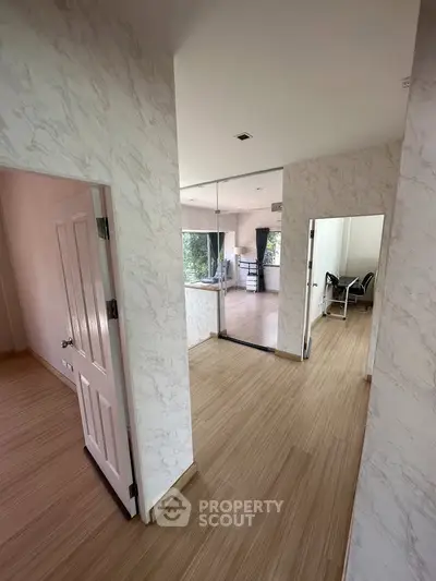 Spacious modern apartment interior with wooden flooring and large windows offering natural light.