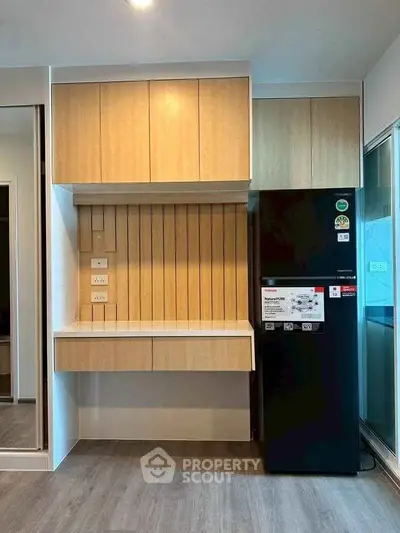 Modern kitchen with sleek cabinetry and black refrigerator in a stylish apartment.